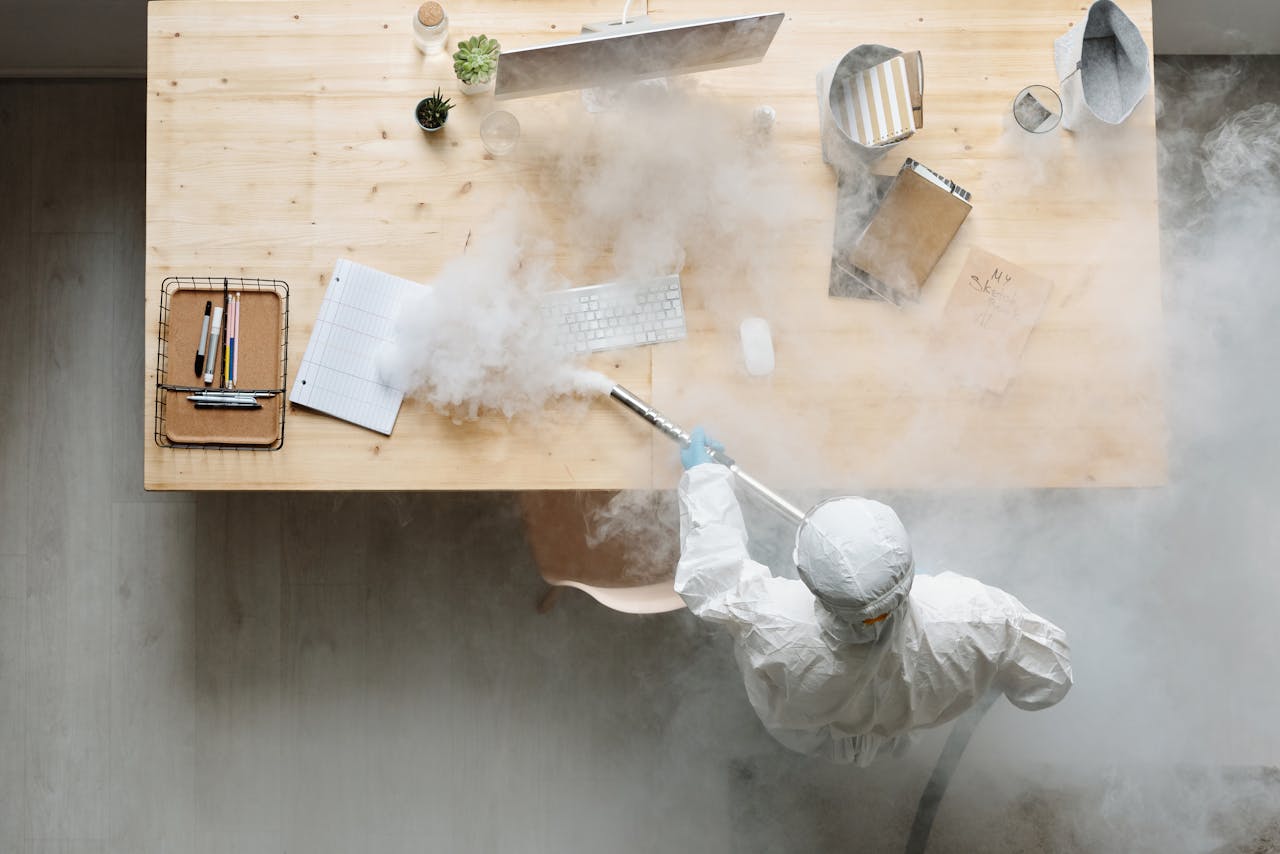 about-us An individual disinfects a workspace using fumigation, wearing full protective gear for safety.